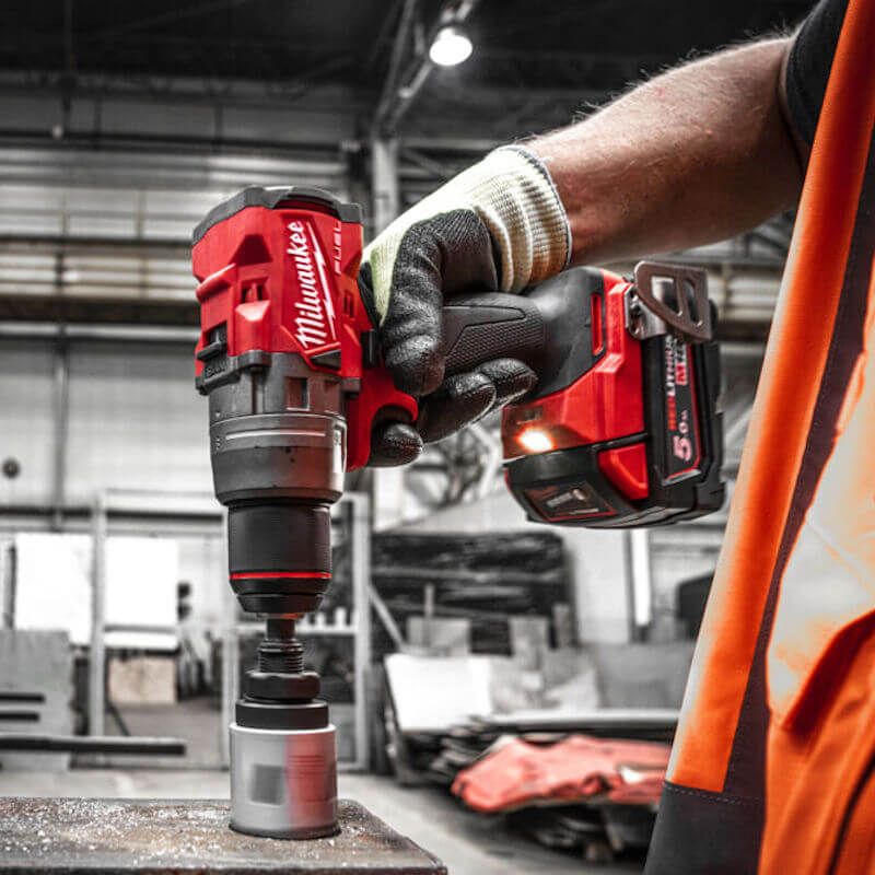 Action shot of the Milwaukee M18 FUEL™ Combi Drill in use, highlighting its powerful 158Nm torque, compact design, and advanced features like the POWERSTATE™ brushless motor and AutoStop™ control mode.