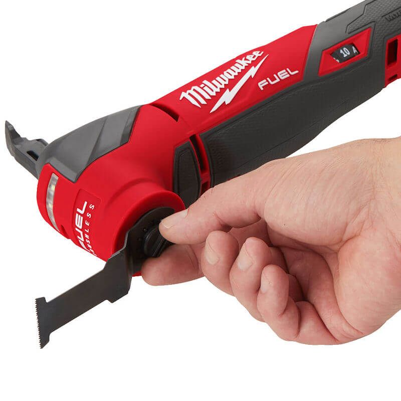 Person changing the blade on the Milwaukee M18 FUEL Multi-Tool using the FIXTEC tool-free blade change system, highlighting its convenience, ergonomic design, and built-in LED light for precision.