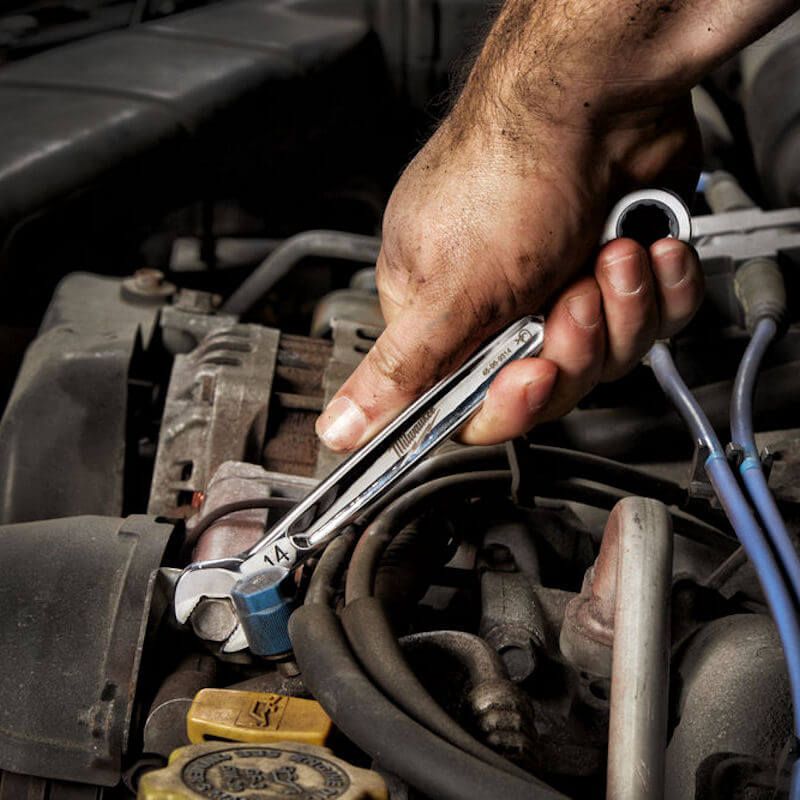 Person using a Milwaukee Maxbite 15pc Ratcheting Combination Spanner Set with ergonomic handles and durable chrome alloy steel.